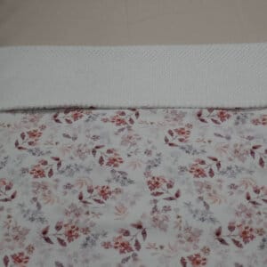 Wiegdeken van fijne wafelstof kleur wit en jerseystof met bloemen in roze paarse tinten.