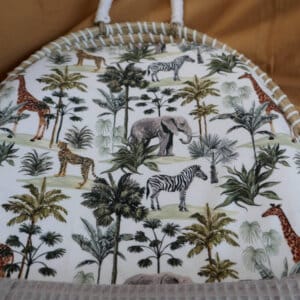 Close-up opgemaakte rieten mand met hoeslaken safariprint en taupe-donkergroene wafelstof.