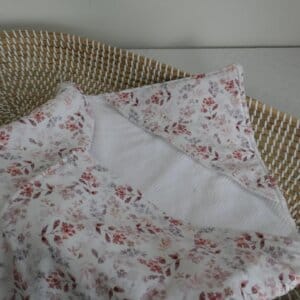 Omslagdoek witte babywafel- en tricotstof met bloemprint in rozetinten.