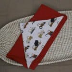 Opgevouwen omslagdoek met buitenzijde voertuigen print en binnenzijde wafeljersey kleur cognac.