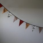 opgehangen katoenen vlaggenlijn met diverse kleuren en print van auto's voorzien van zwart ophangkoord.