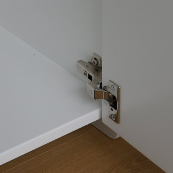 detail softclose deurscharnier van een witte speelgoedkast.
