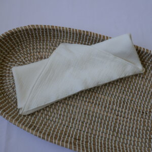 Opgevouwen witte hydrofiele omslagdoek op een rieten ondergrond.