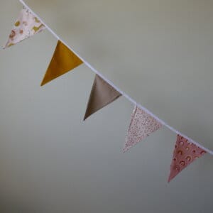 Opgehangen katoenen vlaggenlijn met diverse kleuren en print van regenboogjes, spikkels en safari dieren.